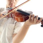 Personne jouant du violon, mettant en valeur la technique et la posture pour tenir l'instrument.