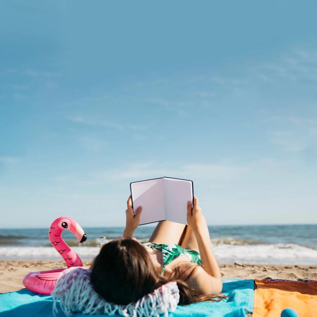 Une jeune femme lit un livre sur la plage pendant les vacances d’été.